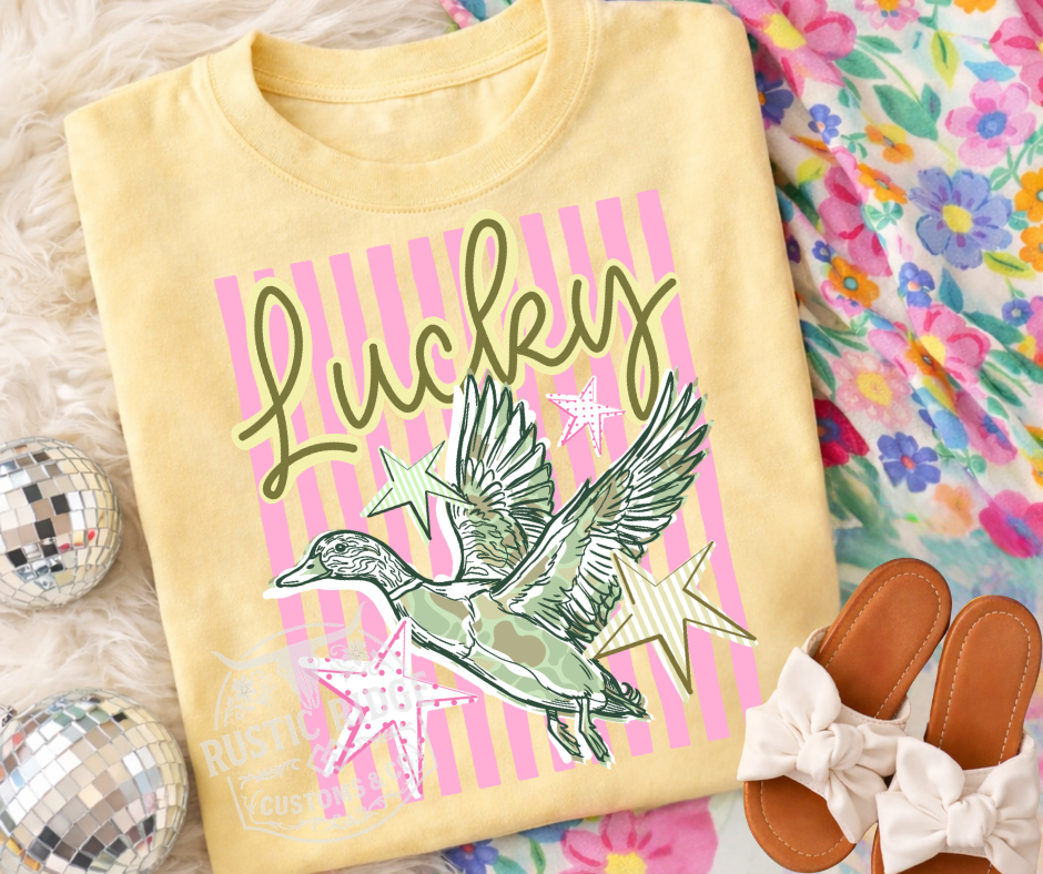 Lucky Duck graphic tee with flying duck and retro pink stripe design on Comfort Colors shirt by Rustic Ridge Customs & Co