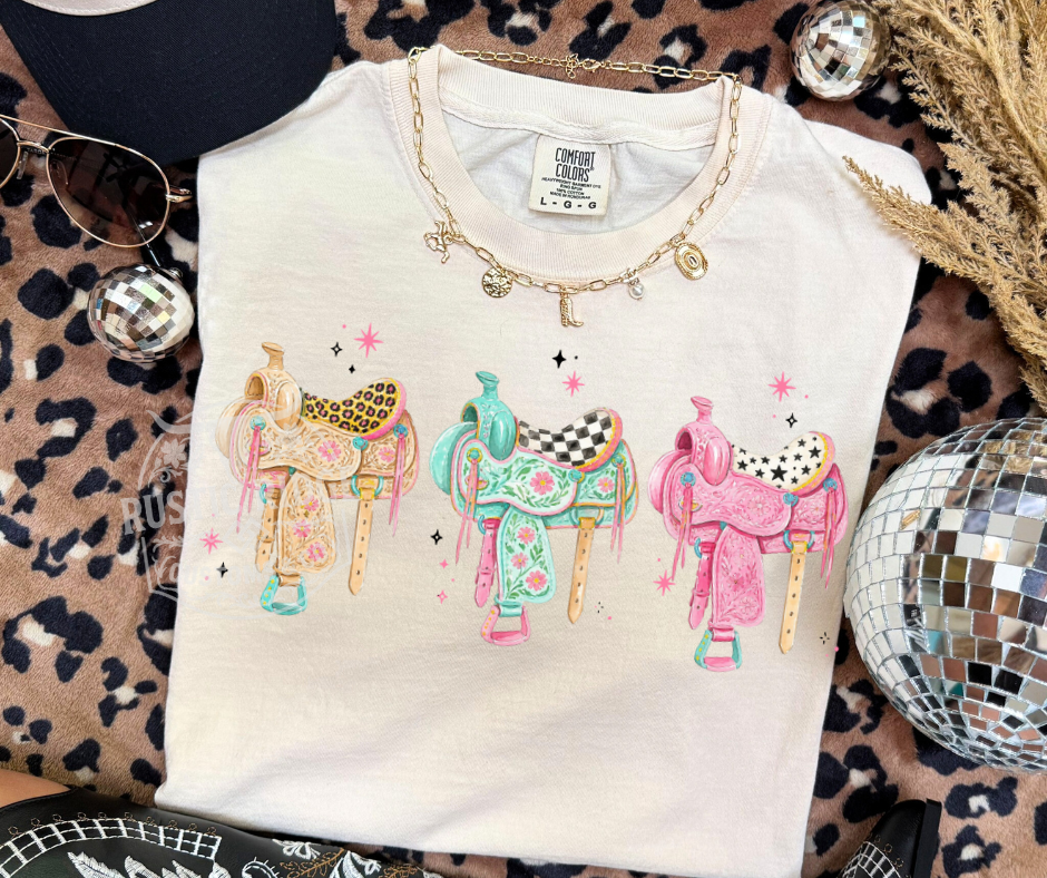 Preppy Trio Saddles western graphic tee with colorful saddle artwork on Comfort Colors shirt by Rustic Ridge Customs & Co