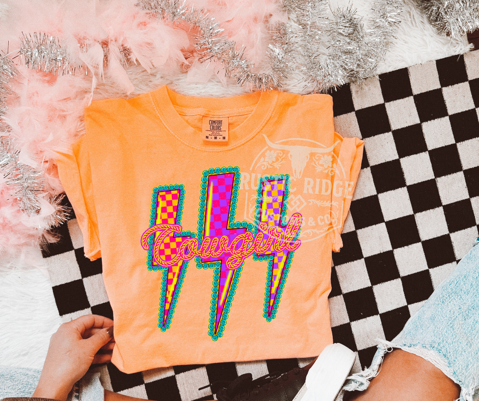 Orange t-shirt with colorful 'Cowgirl' design on a checkered surface