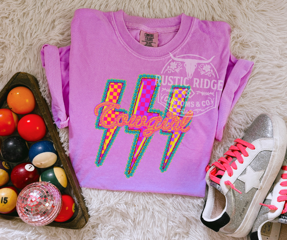 Purple t-shirt with colorful design, sneakers, and pool balls on a textured surface