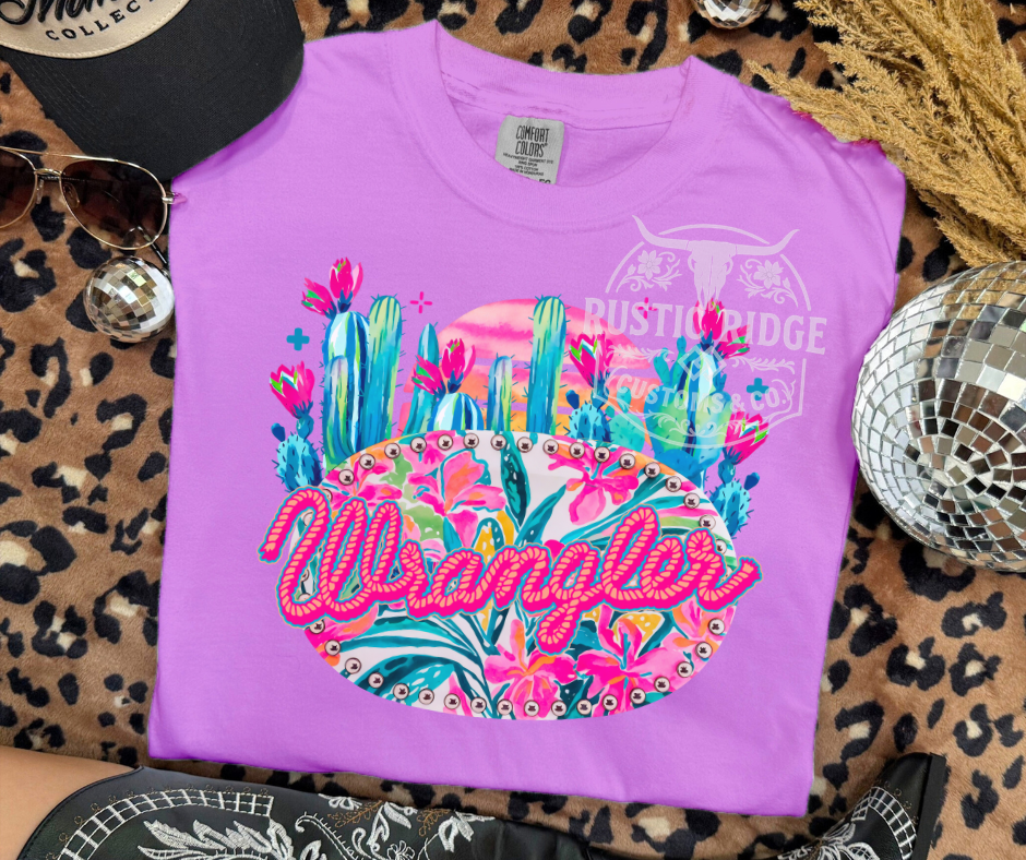 Purple t-shirt with colorful graphic and 'Wrangler' branding on a leopard print surface.