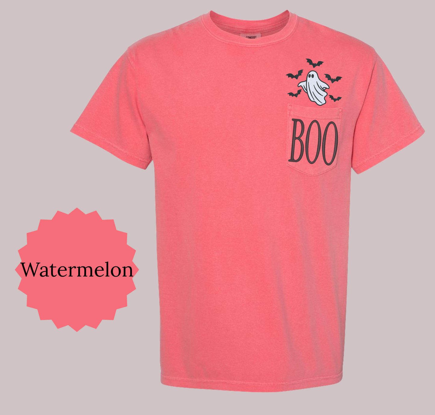 A watermelon pink short-sleeve t-shirt with a Halloween graphic on the left chest featuring a ghost, bats, and the word 'BOO'. A pink scalloped circle overlay on the left reads 'Watermelon'.