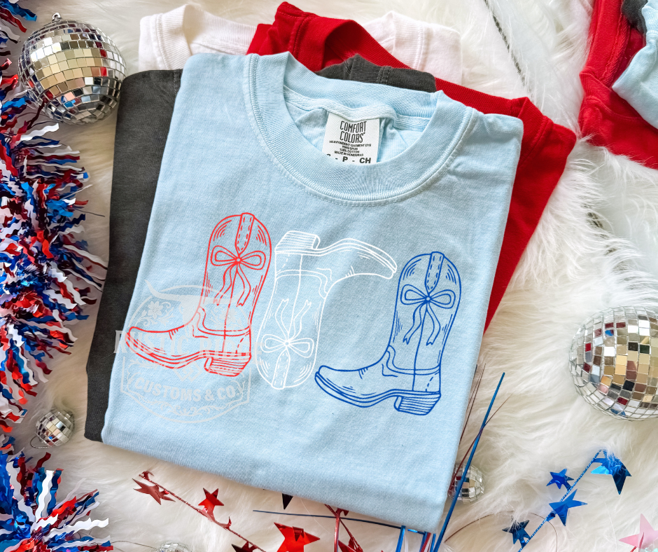 Patriotic graphic tee featuring red white and blue western boots on a Comfort Colors shirt by Rustic Ridge Customs & Co.