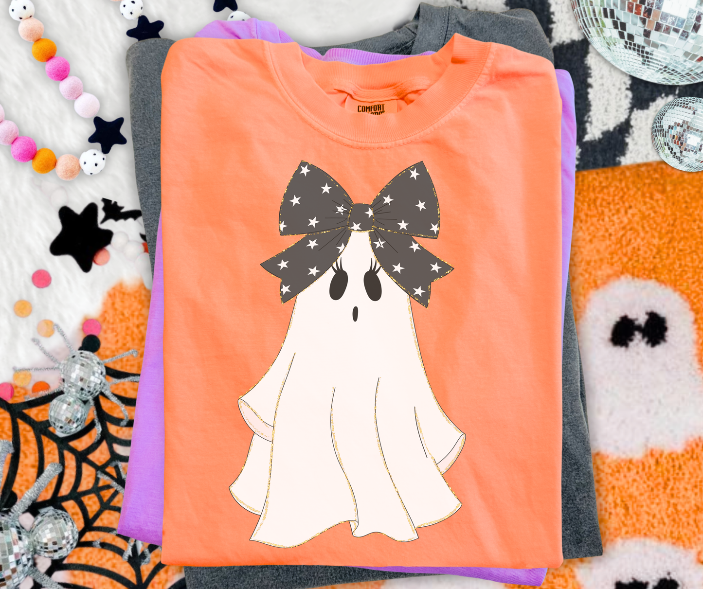 Preppy Bow Ghost Graphic Tee on Neon Cantaloupe Comfort Colors with a white ghost and oversized black star bow