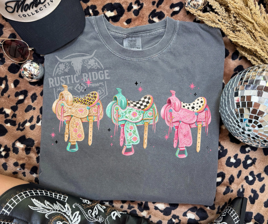 Preppy Trio Saddles western graphic tee with colorful saddle artwork on Comfort Colors shirt by Rustic Ridge Customs & Co