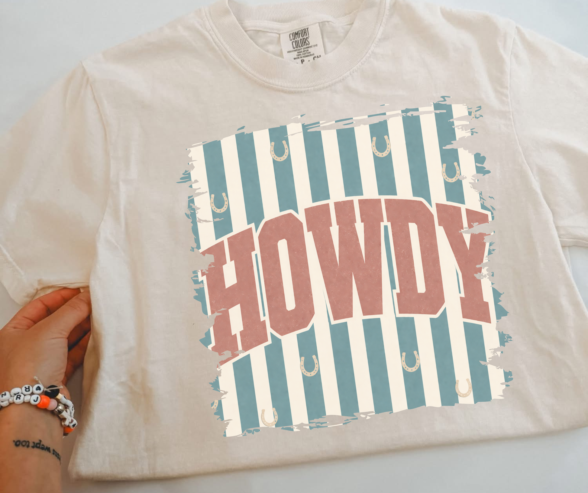 Retro Howdy Western Graphic Tee on an ivory Comfort Colors shirt with blue stripes and horseshoe details