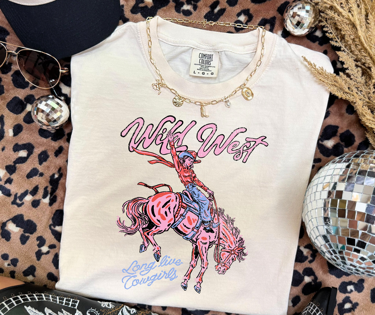 Wild West Cowgirl Graphic Tee on an Ivory Comfort Colors shirt with retro pink cowgirl and bucking horse artwork